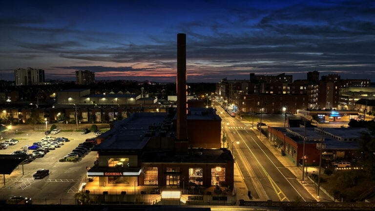 Industrial facility at twilight with smokestacks and highway traffic